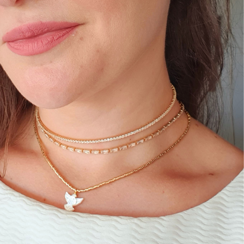 Colar de canutilho com pingente de andorinha e banho em Ouro 18k. Um verdadeiro encanto!  Semijoia perfeita para quem ama delicadeza e não abre mão da elegância para compor os acessórios e looks. Conta com um extensor de 7 cm em sua corrente para garantir o ajuste perfeito para qualquer ocasião. Excelente escolha para quem busca uma peça única, elegante e versátil. 